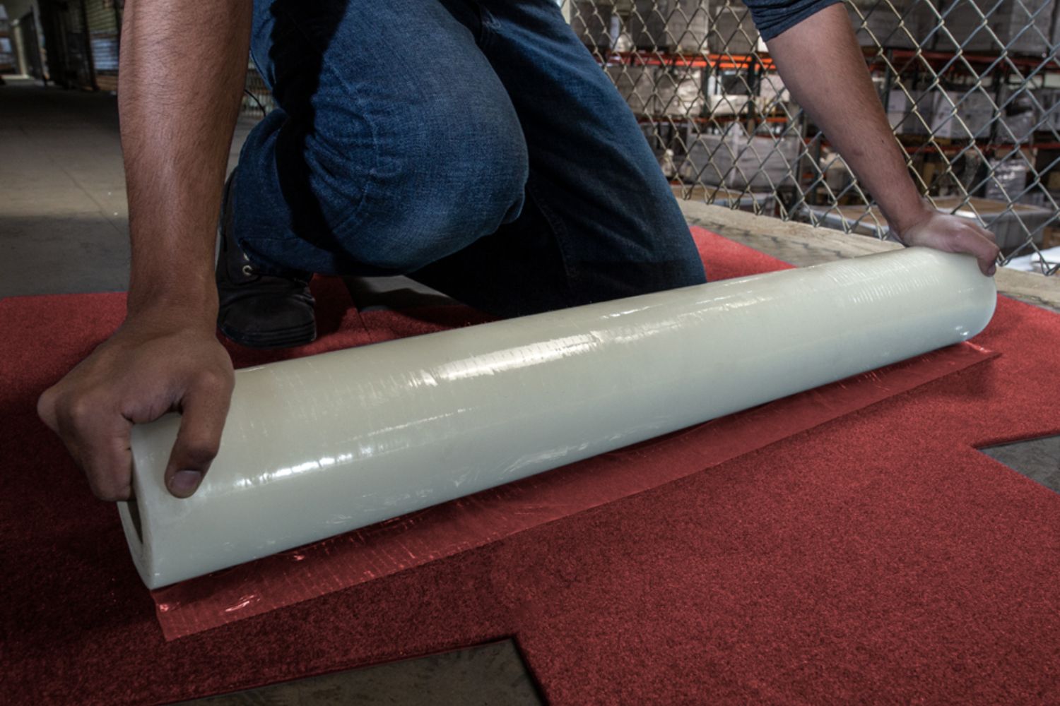 A man places plastic over a red carpet, illustrating a protection and prevention service in Tampa, Florida.