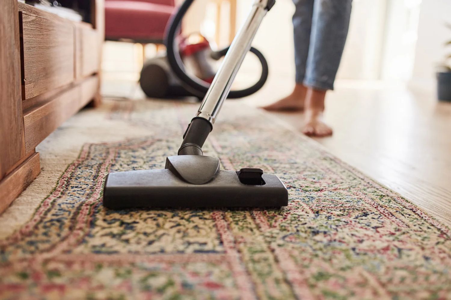 A woman using a vacuum cleaner on a rug, representing a Tampa, FL rug cleaning service.