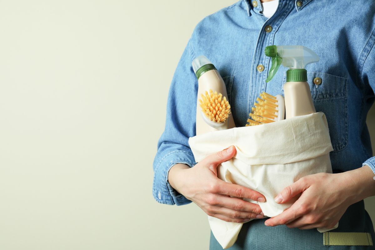 A man holds a bag filled with eco-friendly cleaning supplies for carpet cleaning services.