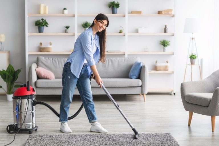 A woman using a vacuum cleaner to clean a carpeted room, representing a professional carpet cleaning service.