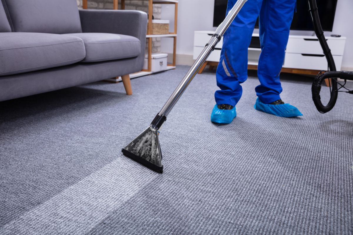 A person using a vacuum cleaner to clean a carpet, representing a professional carpet cleaning service.