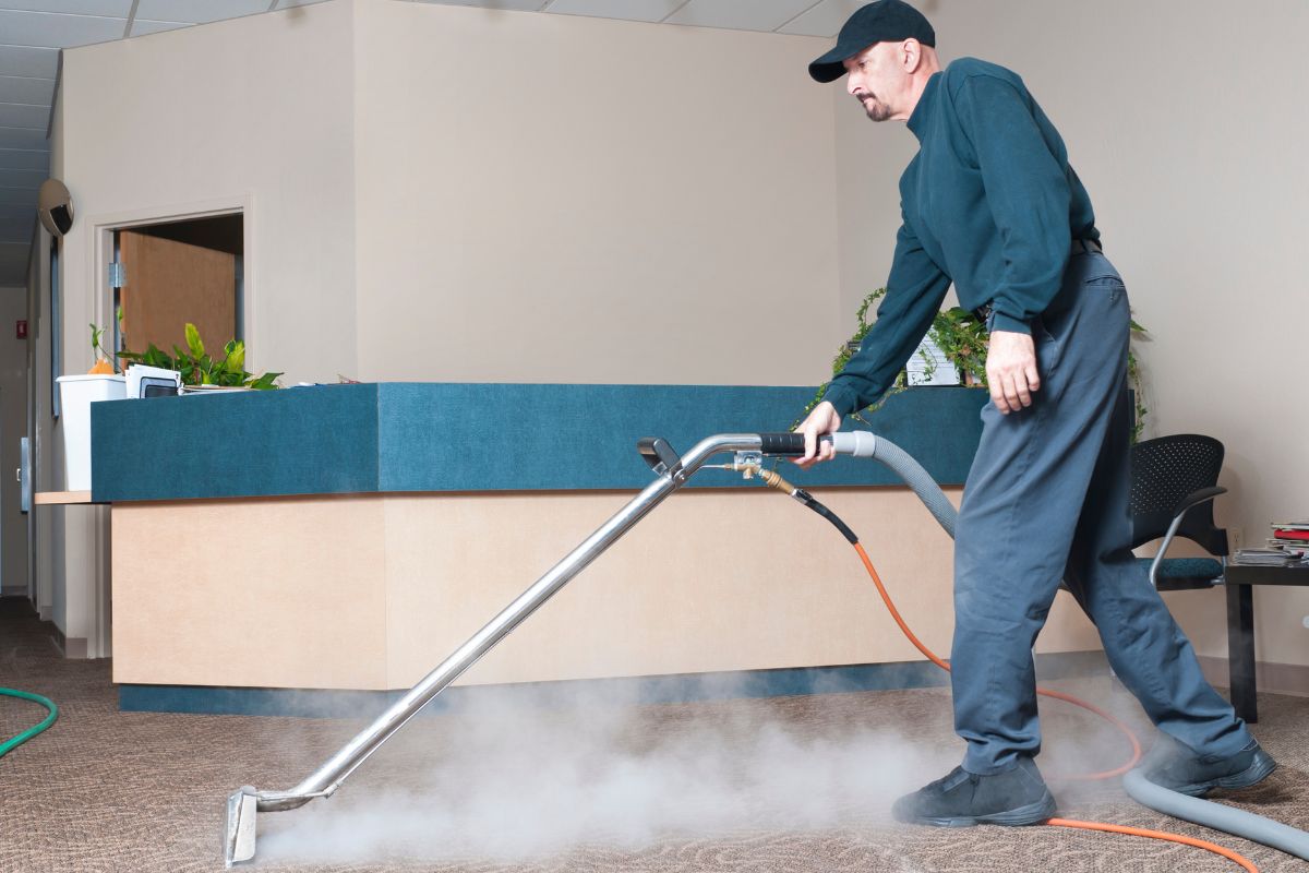 A man operates a vacuum cleaner on a carpet, effectively removing dirt and debris from the surface.